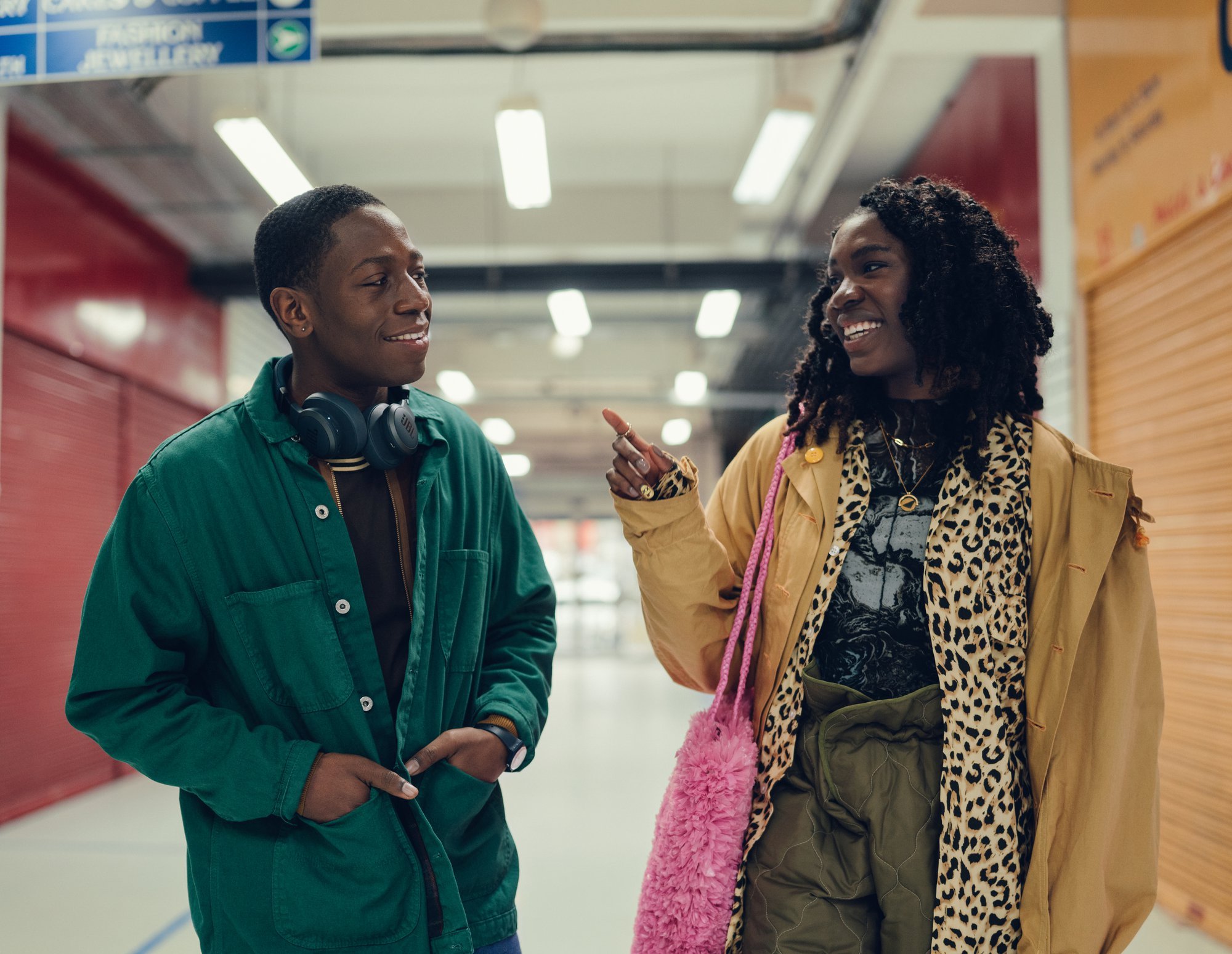'Rye Lane' David Jonsson as Dom and Vivian Oparah as Yas walking down a long hallway while smiling. Yas is pointing at Dom.