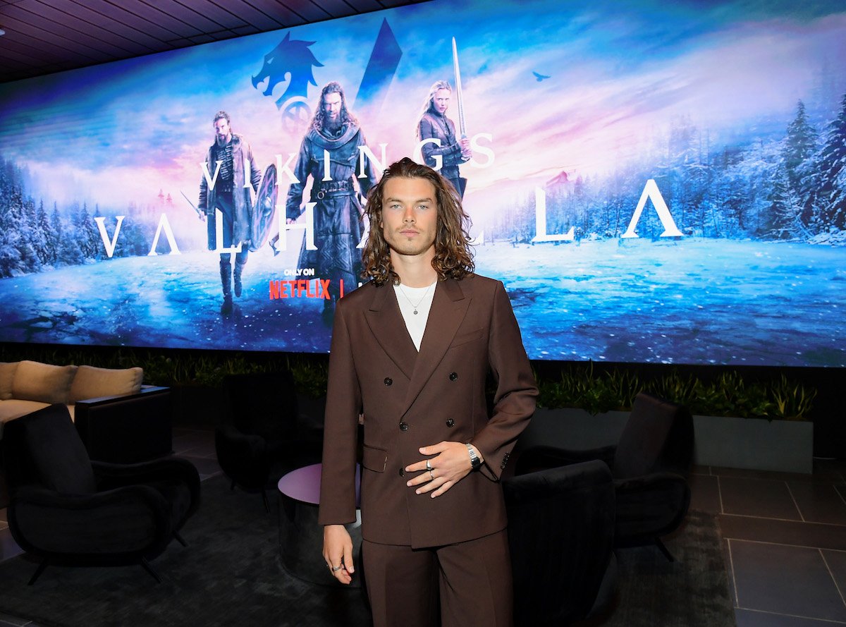 Sam Corlett poises in front of a "Vikings: Valhalla" backdrop at a screening event.
