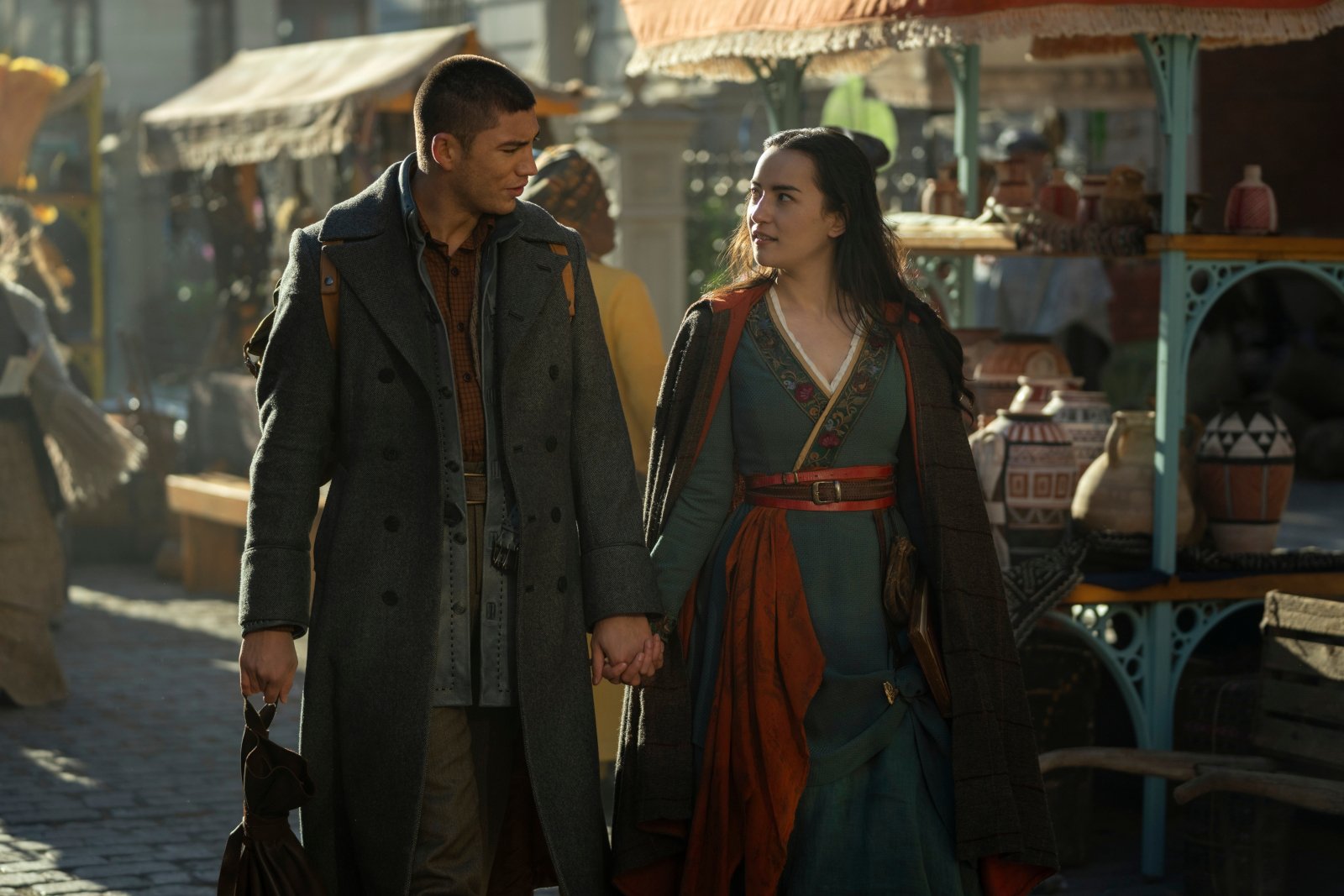 Archie Renaux and Jessie Mei Li as Mal and Alina in 'Shadow and Bone' Season 2 for our article about fantasy shows coming in 2023. They're walking side by side and holding hands.