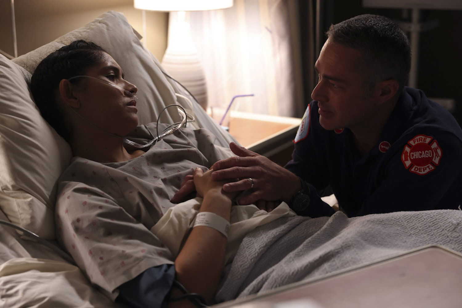 Stella Kidd lies in a hospital bed as Kelly Severide comforts her in Chicago Fire season 11