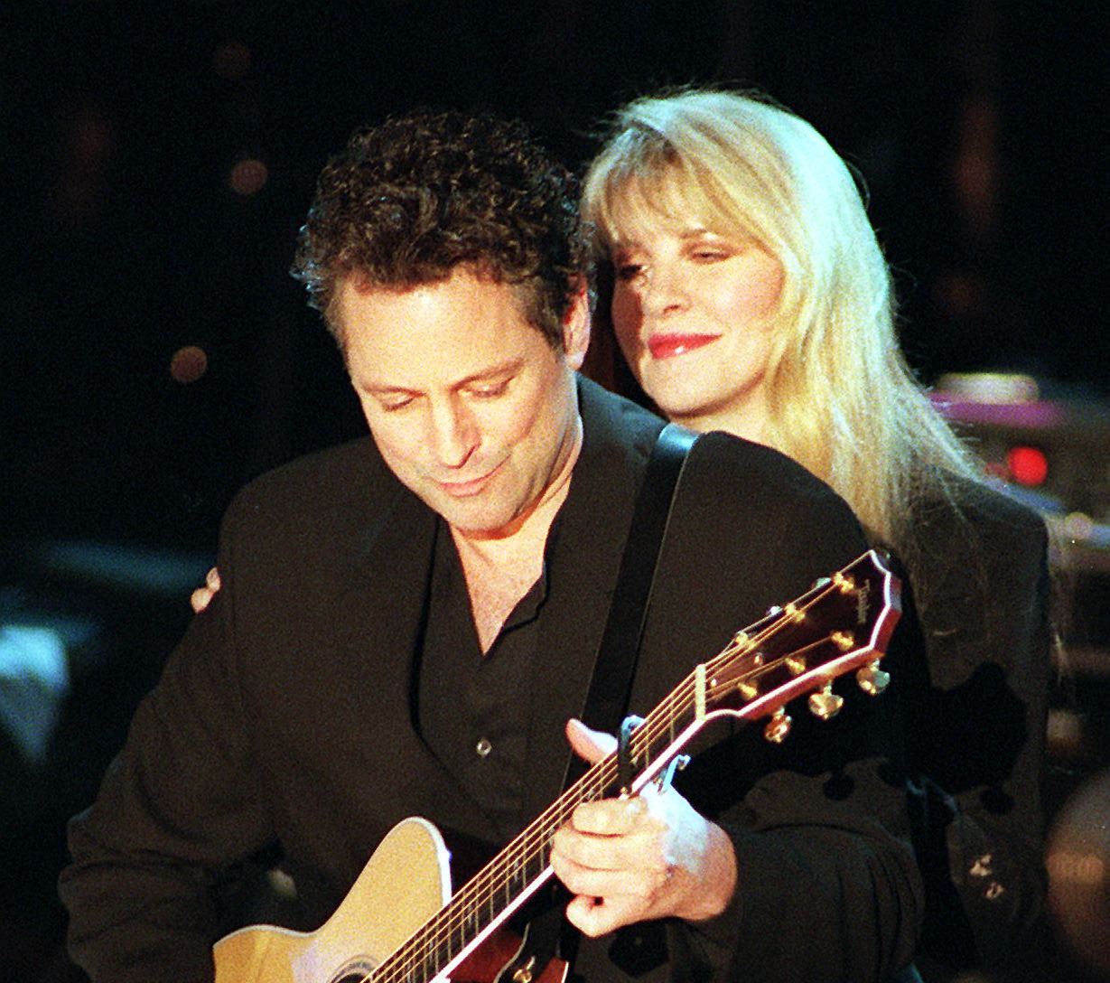 Stevie Nicks looks over Lindsey Buckingham's shoulder as he plays guitar during Fleetwood Mac's Rock & Roll Hall of Fame induction ceremony in 1998.