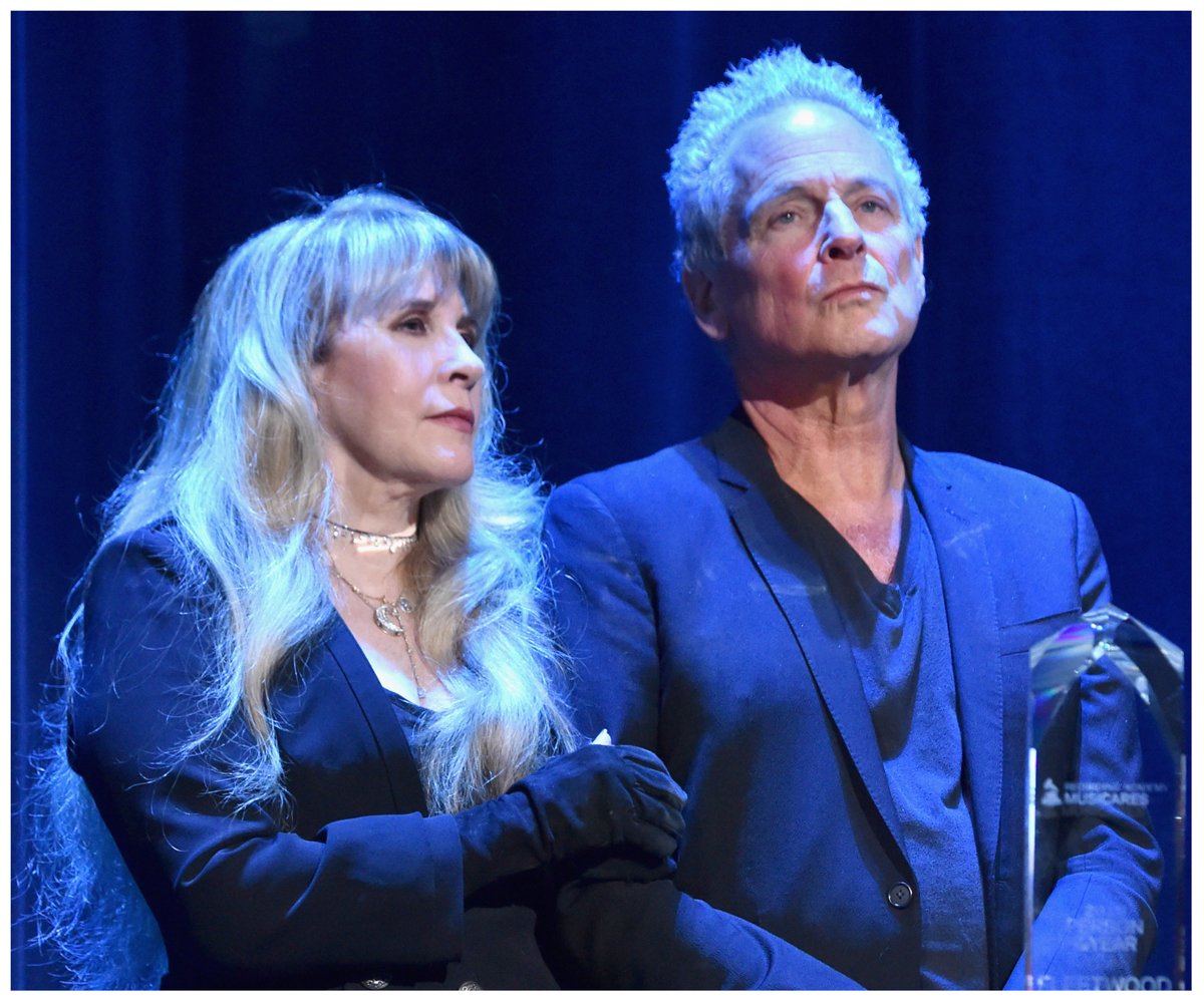 Fleetwood Mac stars Stevie Nicks and Lindsey Buckingham stand together on stage while accepting an award.