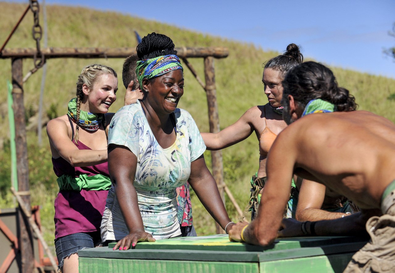 Andrea Boehlke, Cirie Fields, Sarah Lacina and Troyzan Robertson smile standing around a puzzle on the third episode of 'SURVIVOR: Game Changers'.