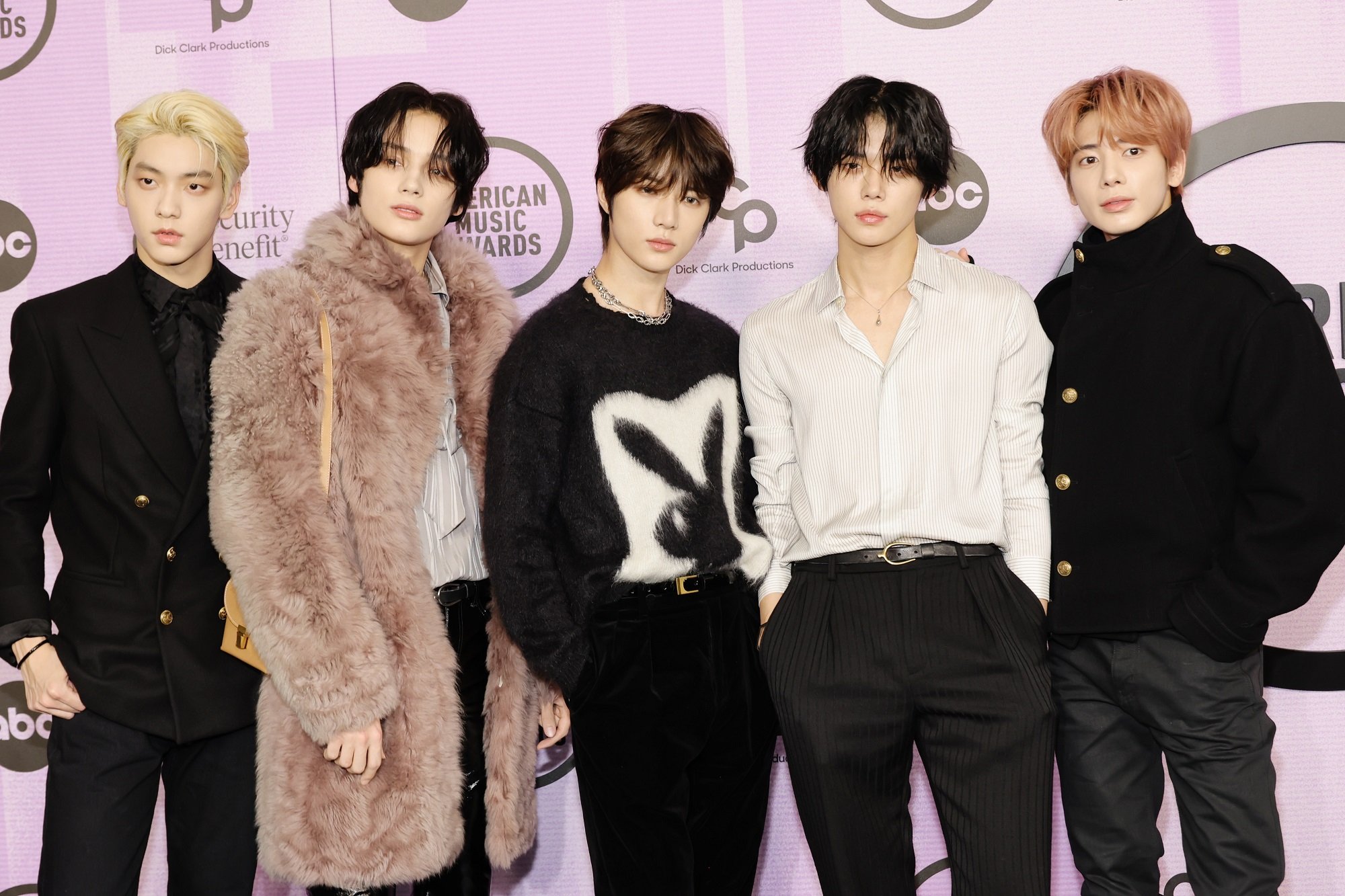 Soobin, Huening Kai, Beomgyu, Yeonjun, and Taehyun of TXT pose together in front of a backdrop that says 'American Music Awards'