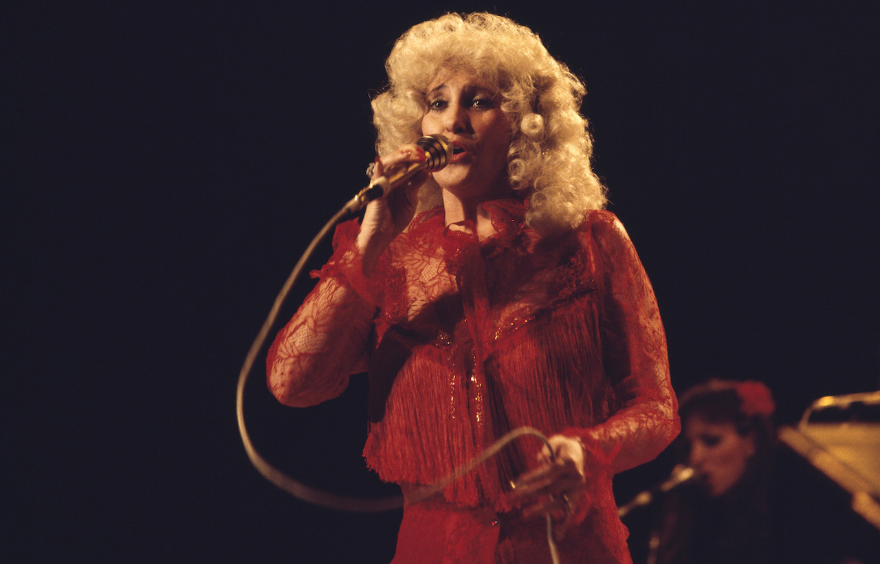 Tammy Wynette pictured singing into a microphone during a live concert.