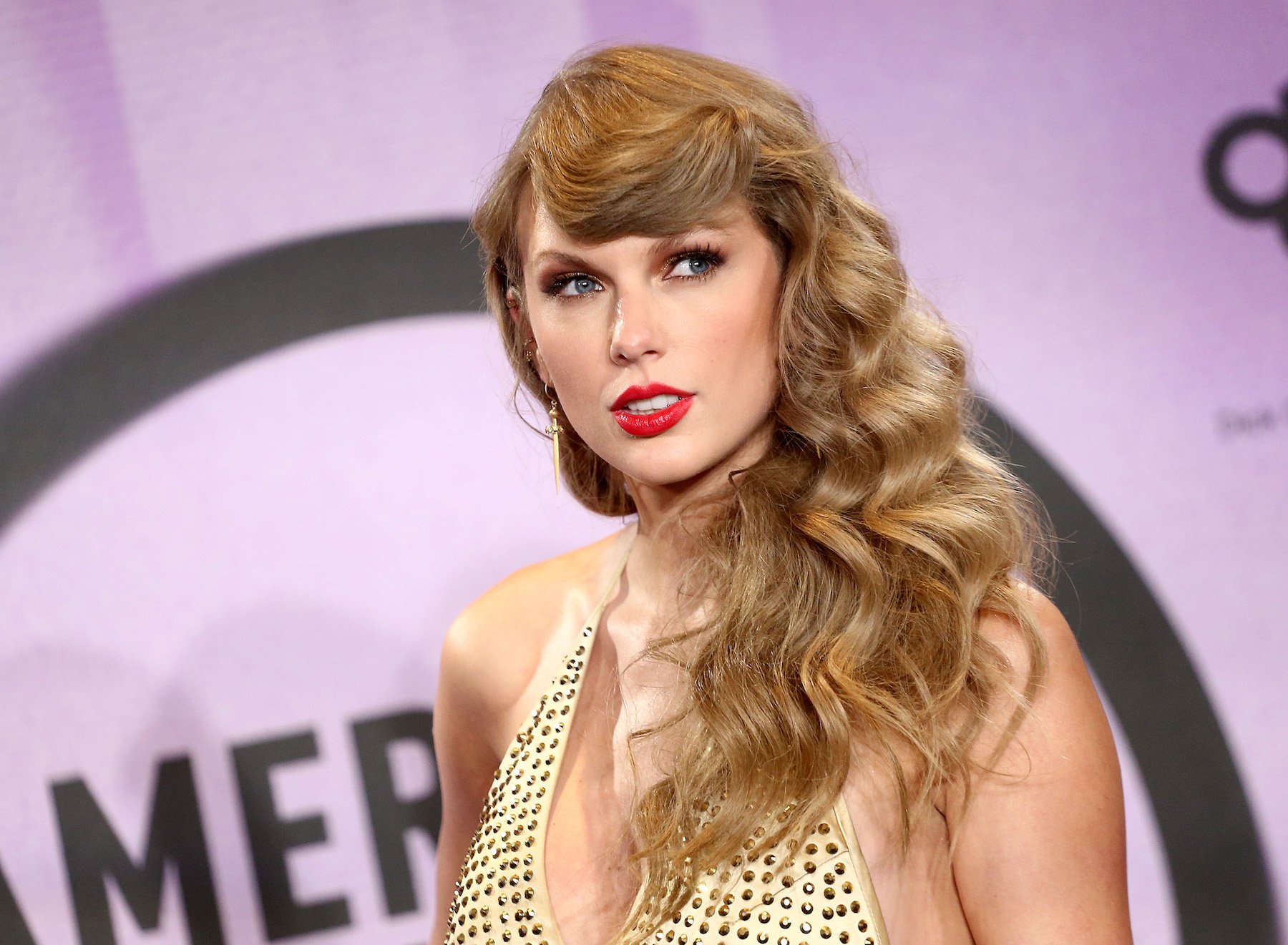 'Midnights' artist Taylor Swift on the red carpet wearing a gold dress