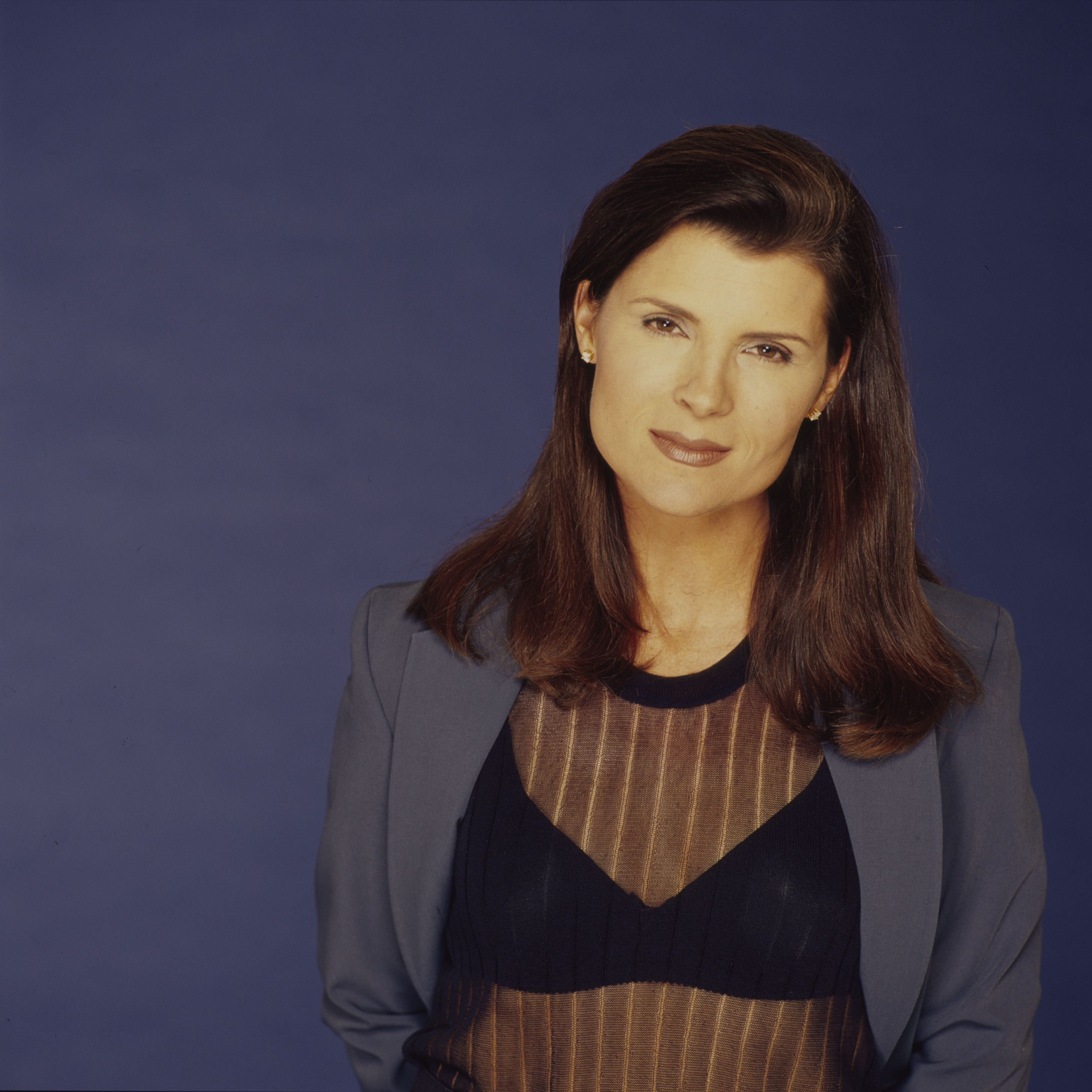 'The Bold and the Beautiful' star Kimberlin Brown in a blue suit, poses in front of a blue backdrop.