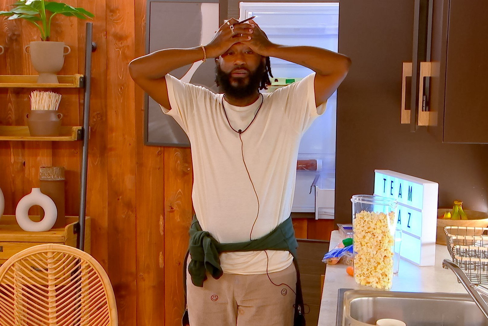 Chaz Lawery, who is one of the contestants in 'The Circle' Season 5 on Netflix, wears a white shirt, tan pants, and a dark green hoodie tied around his waist.