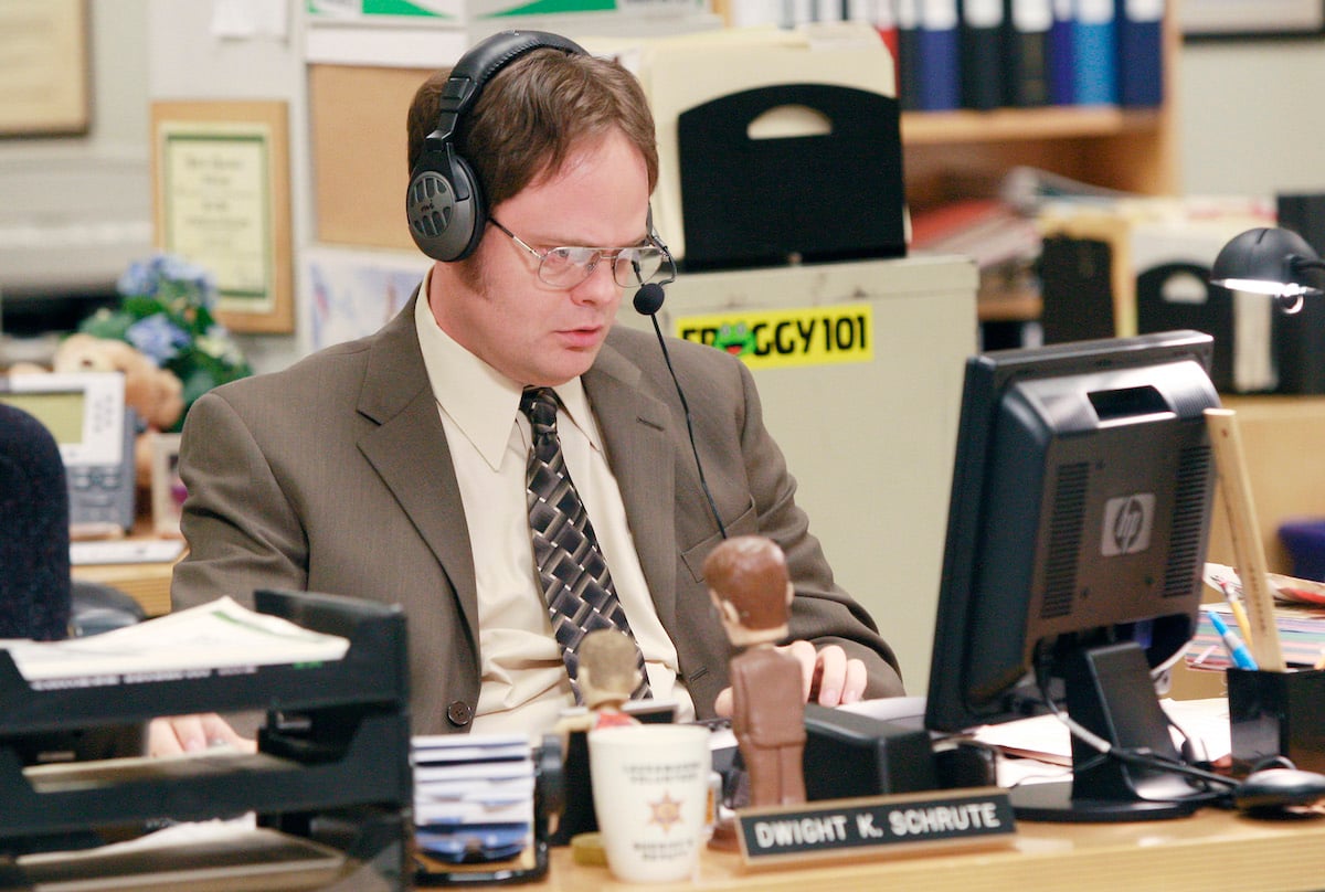 The Office: Dwight Schrute (Rainn Wilson) sits at his desk wearing a headset