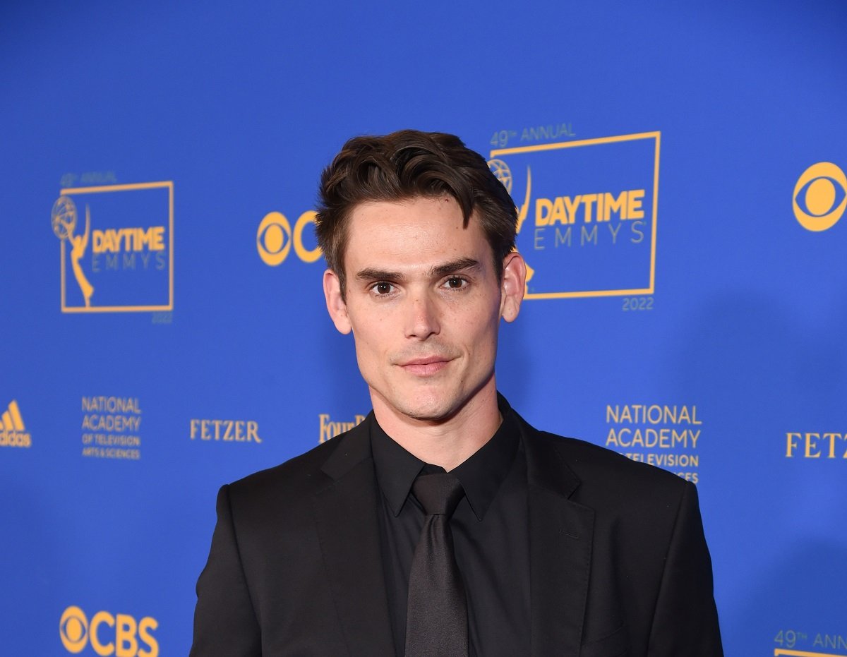 'The Young and the Restless' star Mark Grossman wearing a black suit; poses on the red carpet of the 2022 Daytime Emmys.