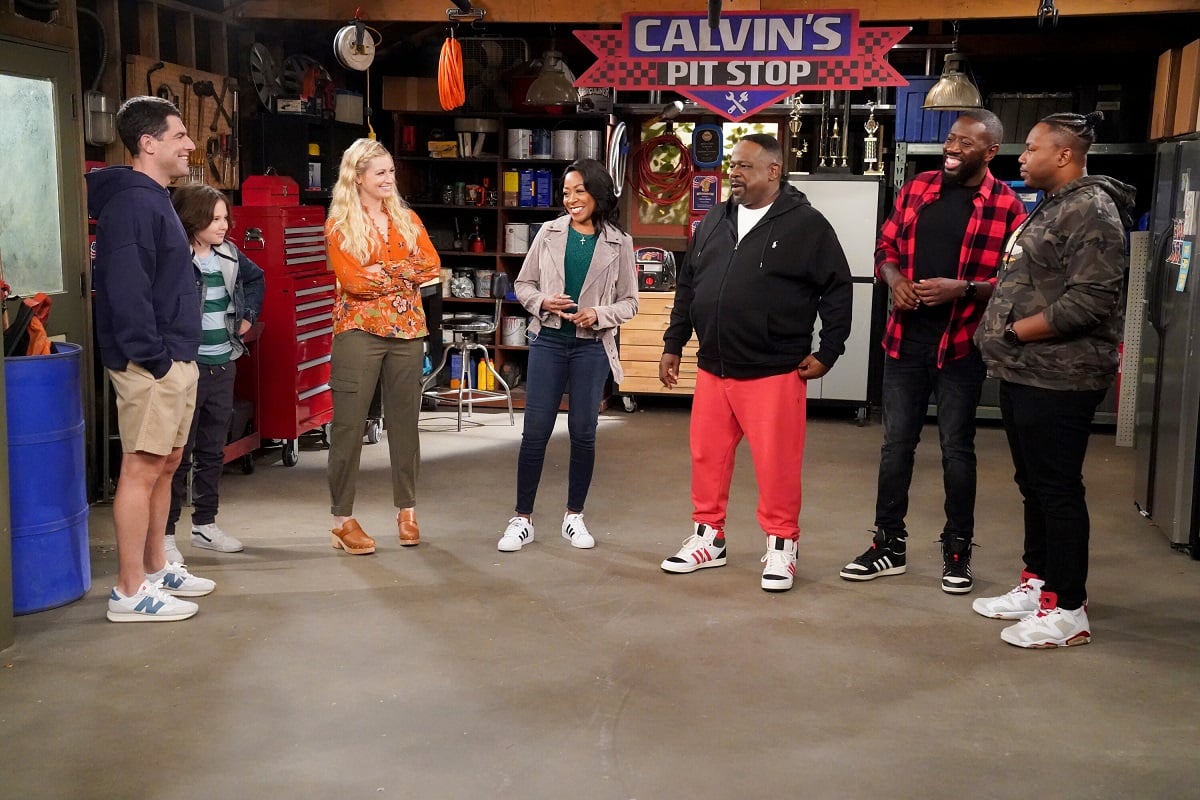 The cast of 'The Neighborhood' stand around a garage in the season 5 episode 'Welcom to the Getaway'
