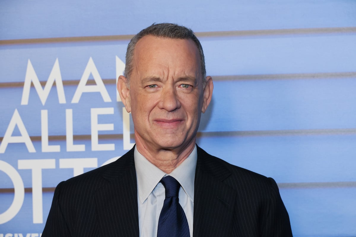 Tom Hanks smiles in front of a blue backdrop at the "A Man Called Otto" premiere.