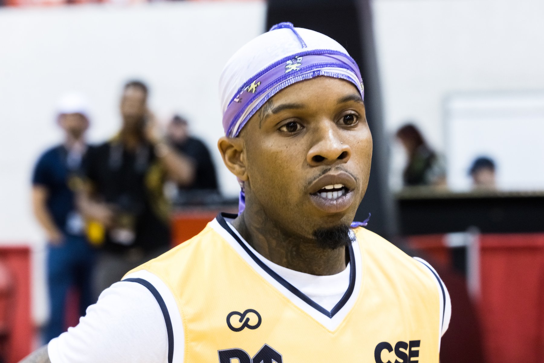 Tory Lanez, who just hired Snoop Dogg's former lawyer, wearing a yellow jersey and purple durag