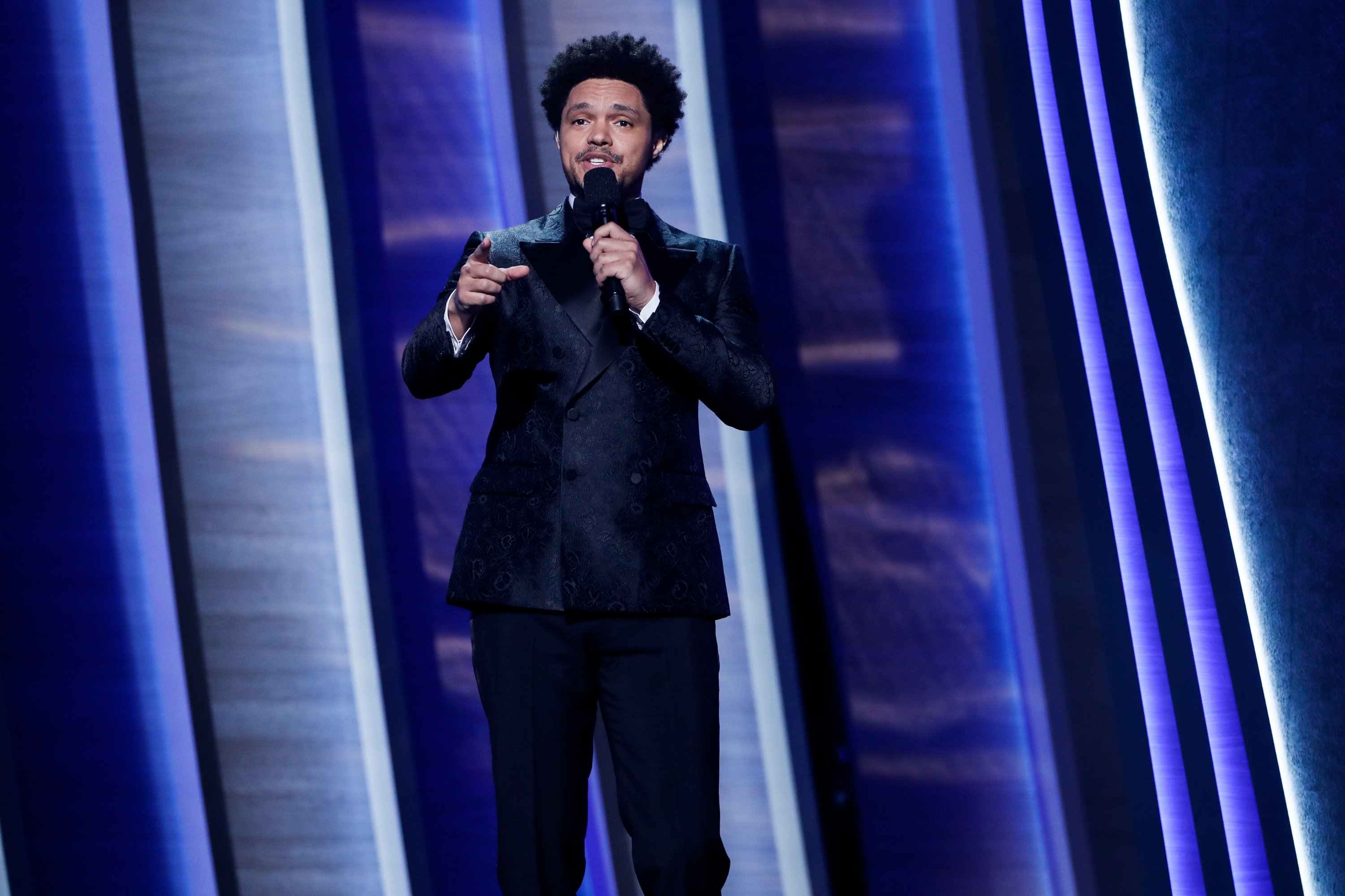 Trevor Noah stands on stage speaking into a microphone