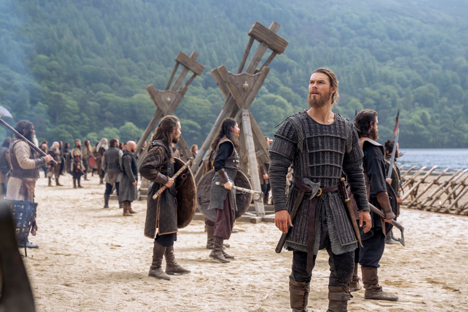 Sam Corlett as Leif Eriksson in 'Vikings: Valhalla' Season 1 for our recap of the first outing. He's looking up at something, and there are men and ships behind him.