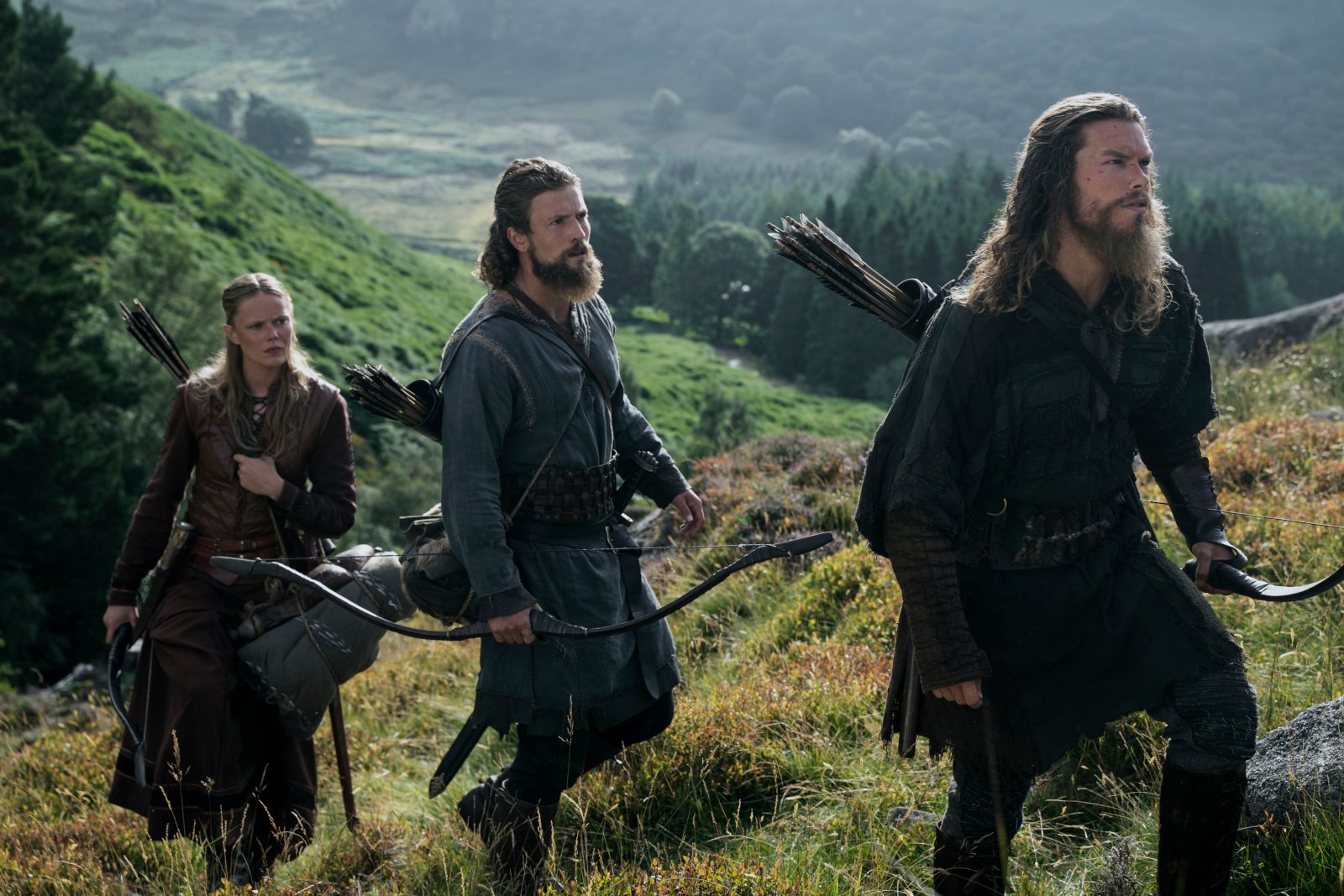 Frida Gustavsson, Leo Suter, Sam Corlett in 'Vikings: Valhalla' Season 2 for our article about its release date. They're walking up a grassy hill.