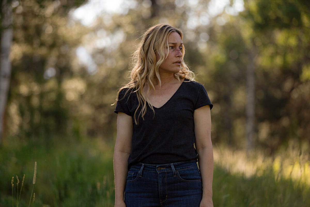 In Yellowstone Season 5, Summer stands on the Dutton land wearing jeans and a black v-neck shirt. She has a bruise on her face.