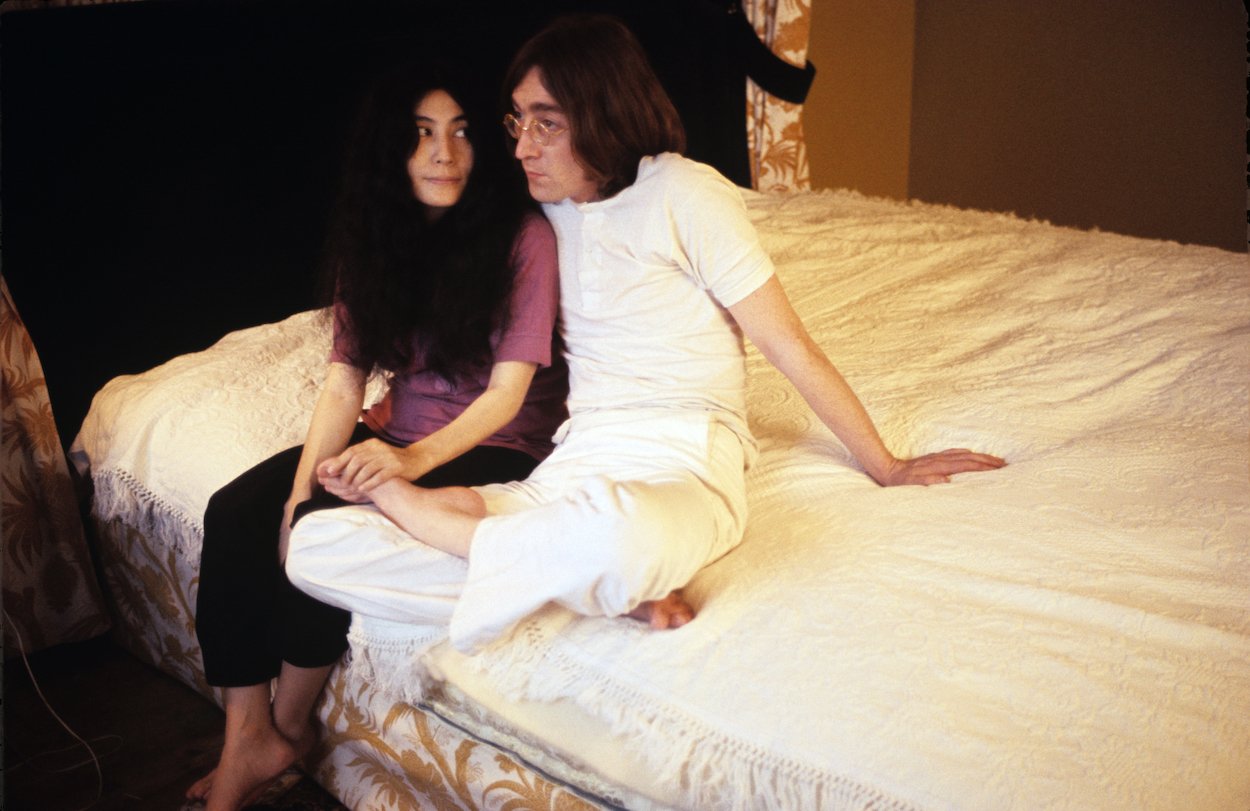 Yoko Ono (left) and John Lennon of The Beatles sitting together on a bed in December 1968.