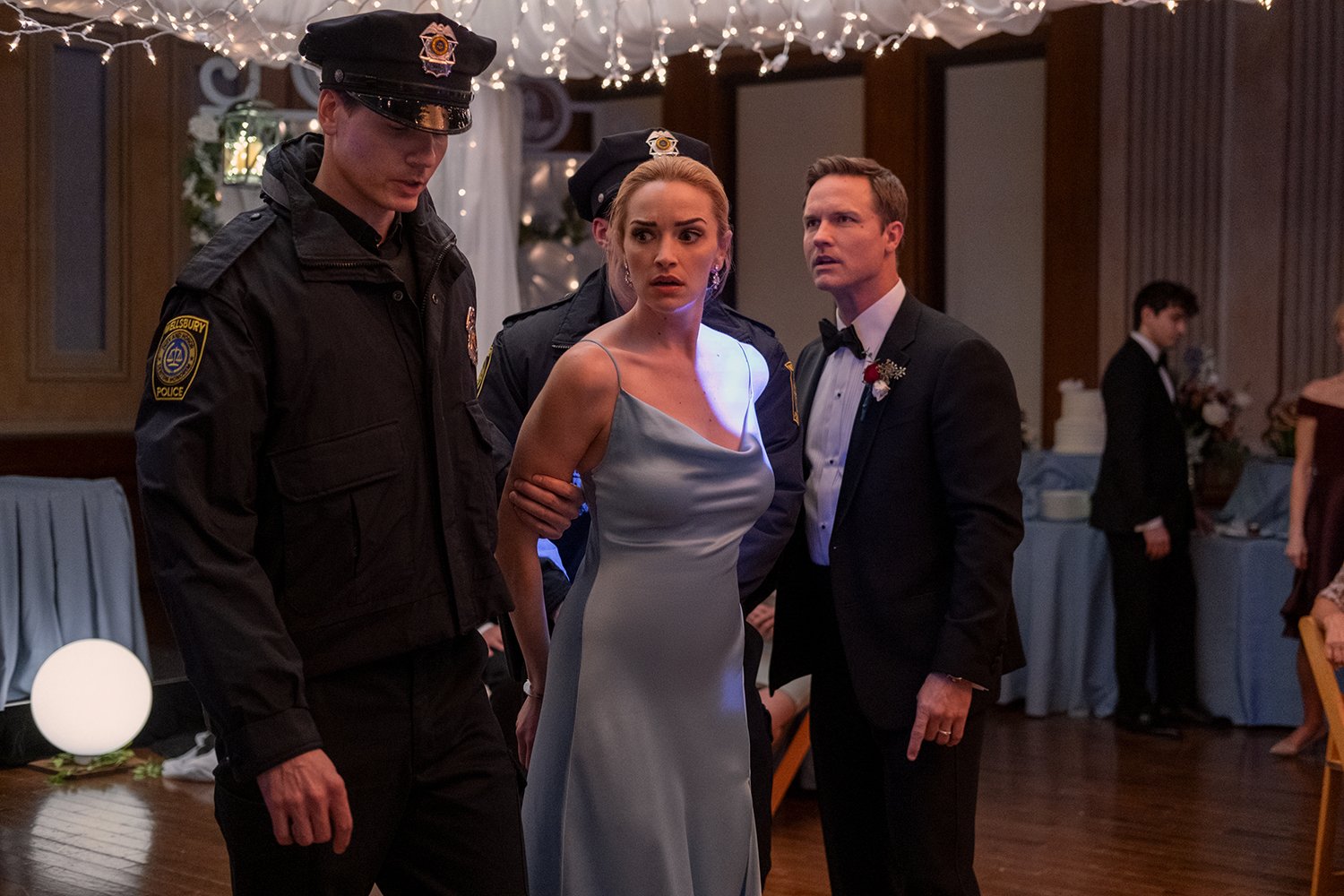 Ginny & Georgia Season 2: Brianne Howey's Georgia Miller gets escorted out of her wedding reception by a policeman as Scott Porter's Paul Randolph watches in shock.