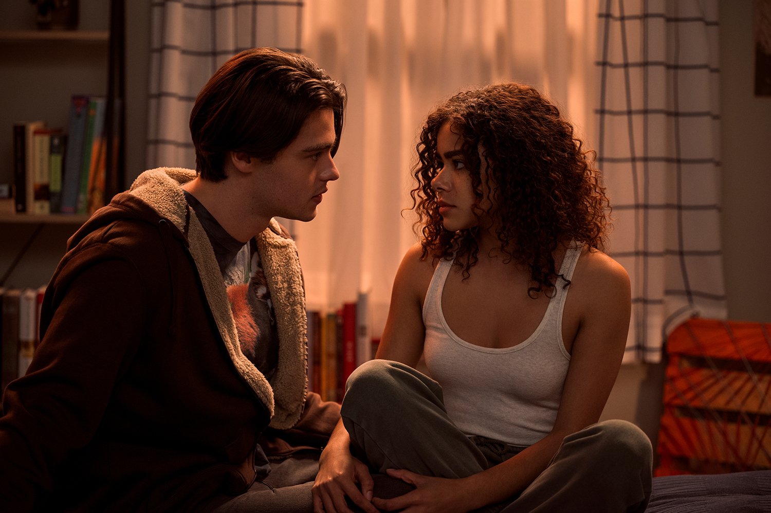 Felix Mallard as Marcus Baker and Antonia Gentry as Georgia Miller sitting on Ginny's bed together in Ginny & Georgia Season 2