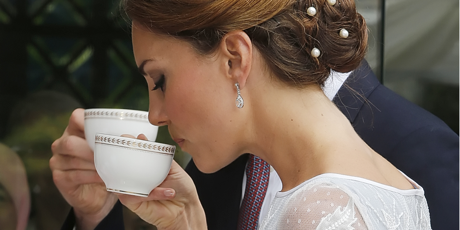 Kate Middleton drinking a cup of tea at a formal event.