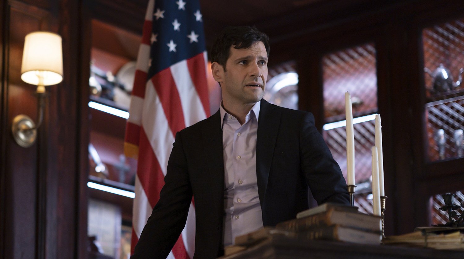 National Treasure: Edge of History star Justin Bartha as Riley Poole in a suit with a concerned expression