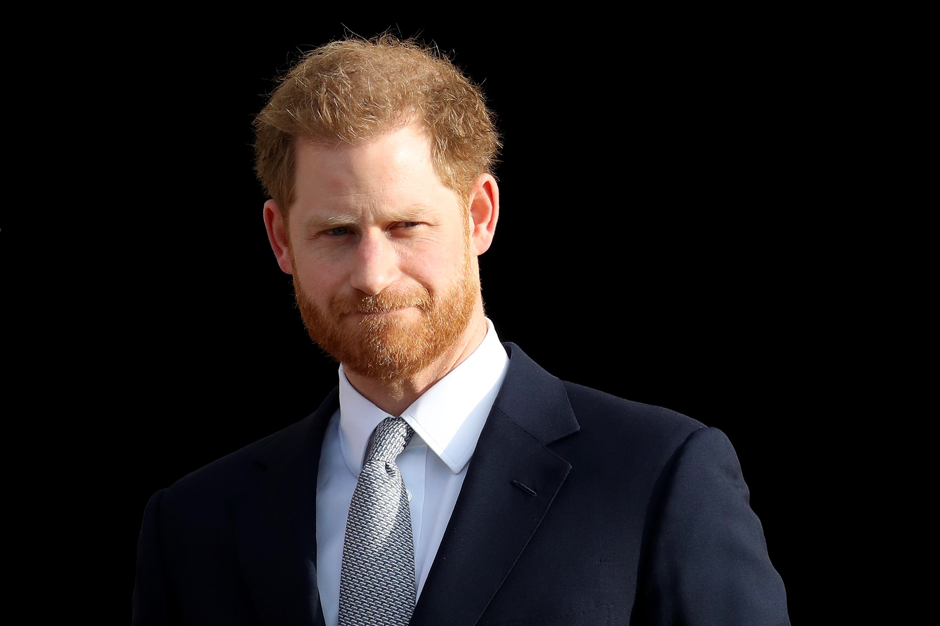 Prince Harry poses in a dark suit.