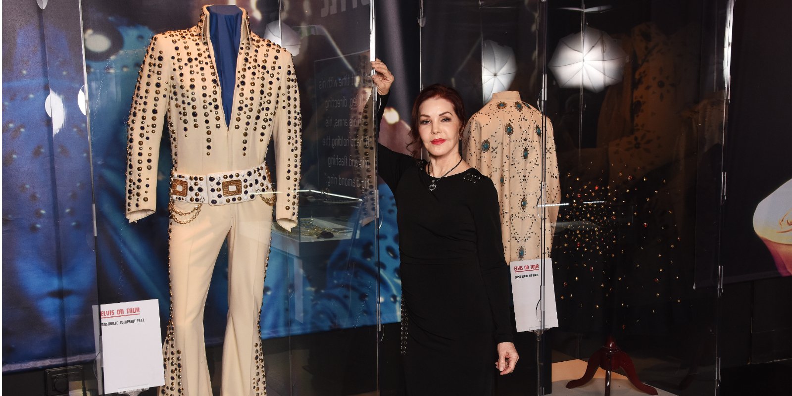 Priscilla Presley poses with Elvis Presley's jumpsuits.