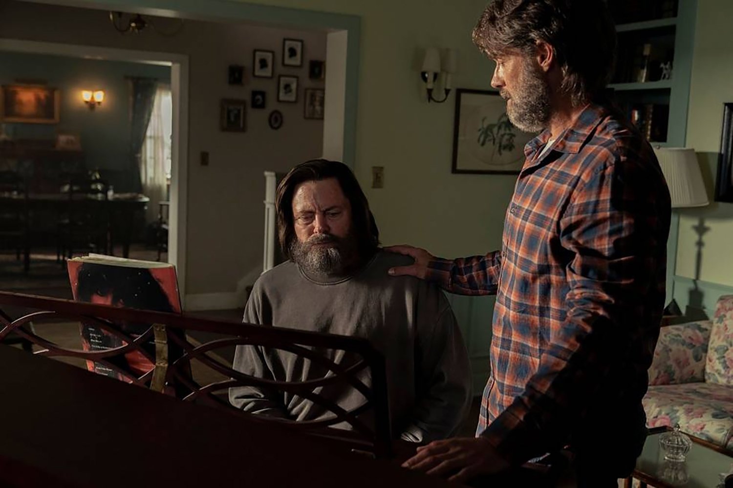 The Last of Us: Nick Offerman as Bill sitting at a piano while Murray Bartlett's Frank stands beside him with a hand on Bill's shoulder