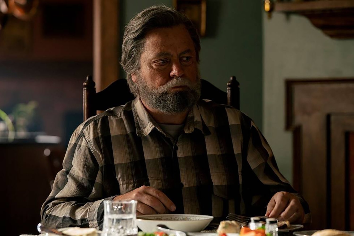 Nick Offerman as Bill sitting at a dining table in The Last of Us Episode 3.