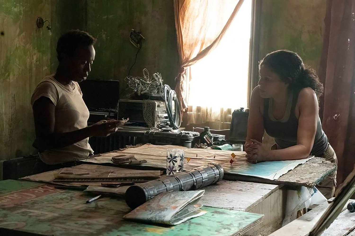 The Last of Us: Natasha Mumba as Kim and Merle Dandridge as Fireflies leader Marlene standing around a cluttered table.