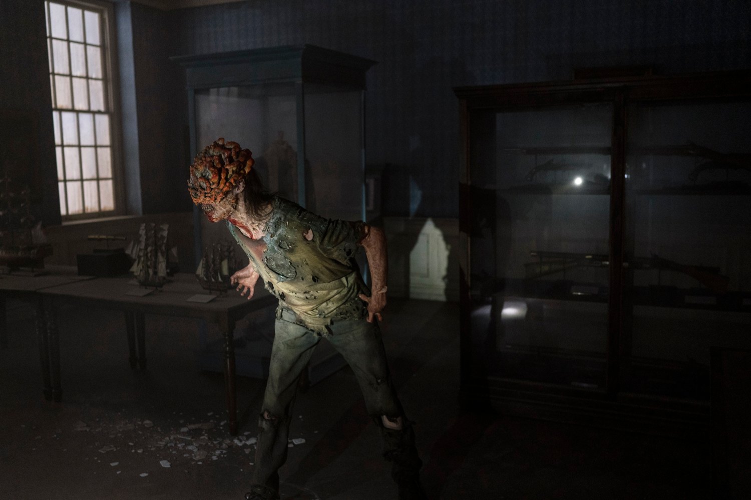 An infected person known as a Clicker roams a dark museum in The Last of Us.