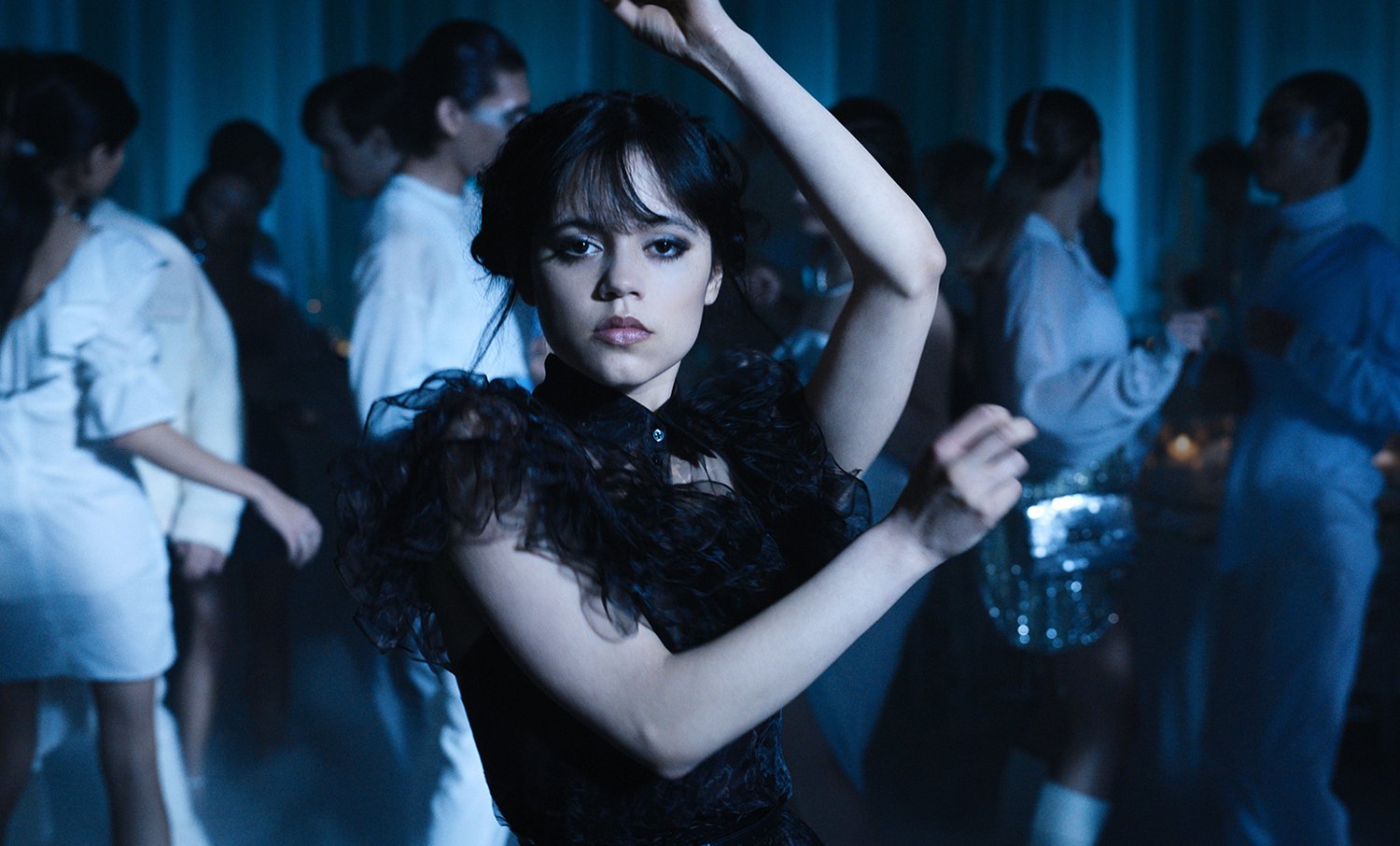 Jenna Ortega with her arms raised as she performs the viral Wednesday Addams dance in Wednesday on Netflix.