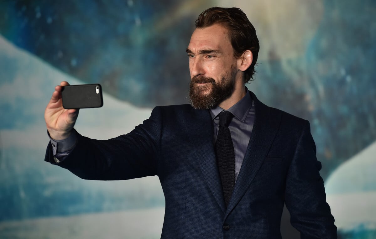 1923 actor Joseph Mawle takes a selfie wearing a dark blue suit jacket with a black tie.