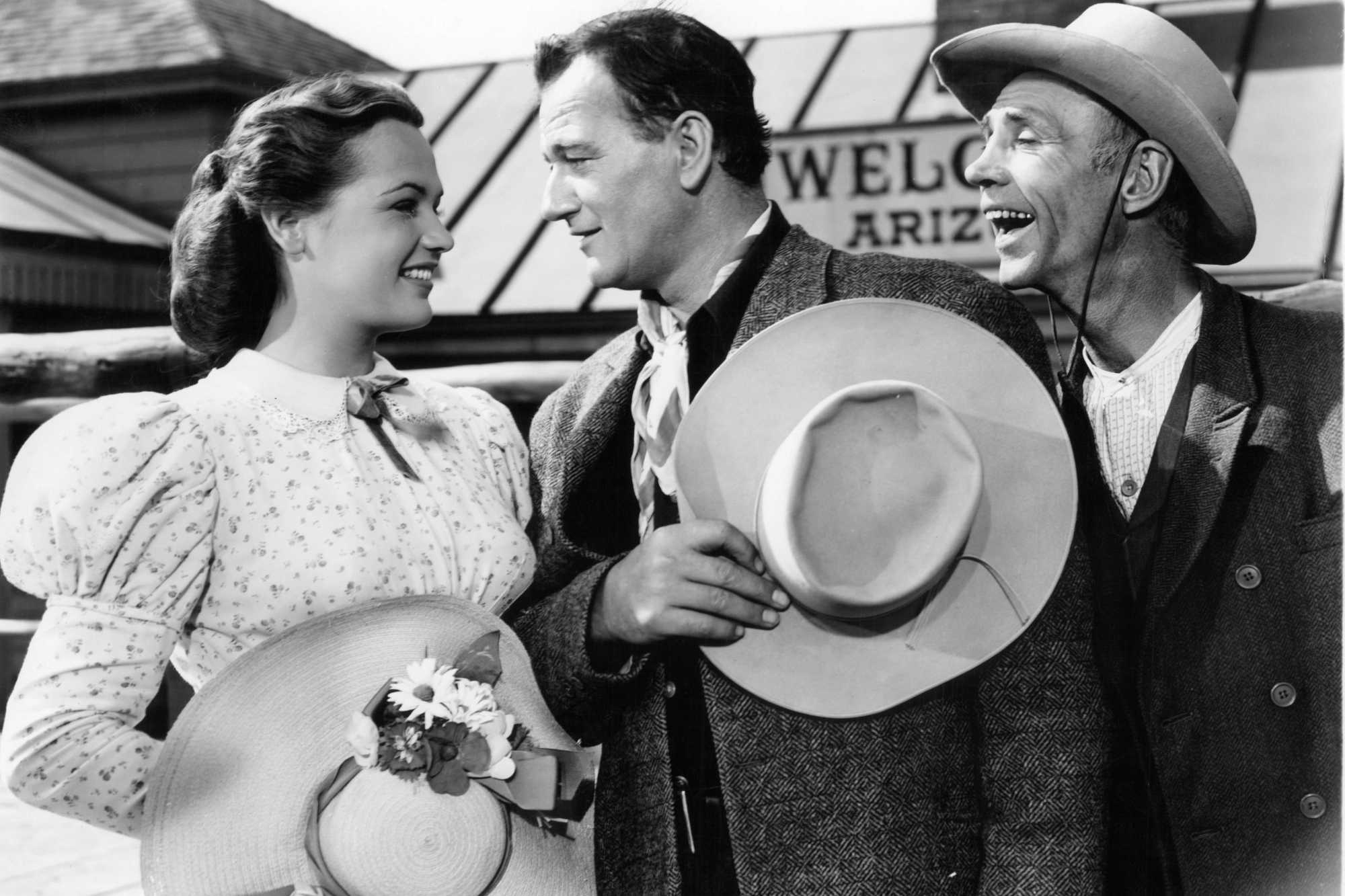 '3 Godfathers' Dorothy Ford as Ruby Latham and John Wayne as Robert Marmaduke Sangster Hightower. Wayne and Ford are looking into each other's eyes, while a man watches.