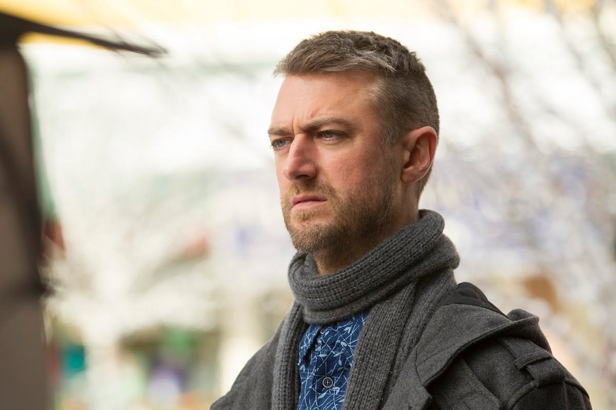 Sean Gunn (as Kirk Gleason) wears a grey coat and scarf in 'Gilmore Girls: A Year in the Life'