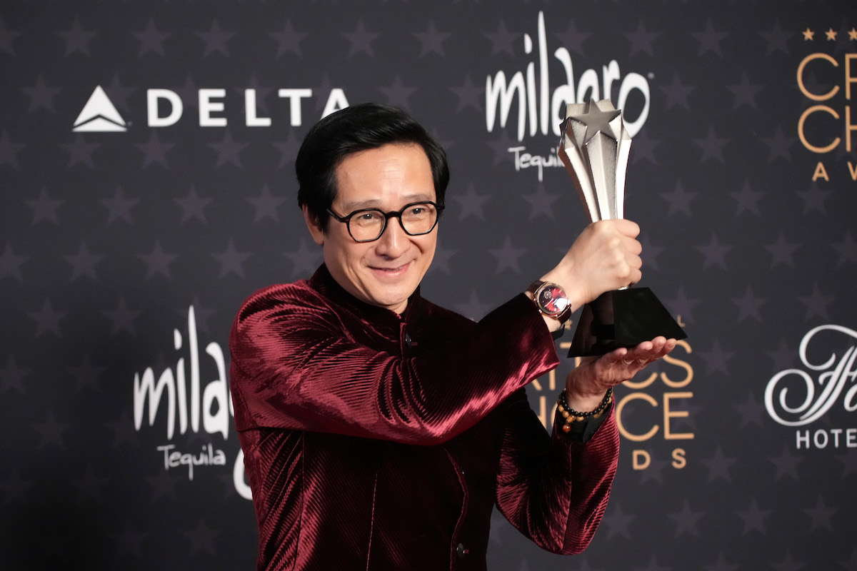 Ke Huy Quan holds up his award at the 28th Annual Critics Choice Awards while wearing a velvet blazer