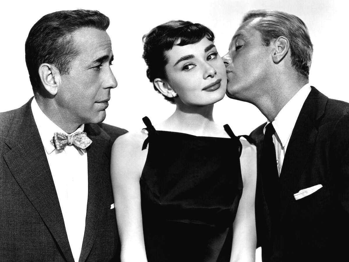 Actors Humphrey Bogart and William Holden look at Audrey Hepburn adoringly during promo photos for Serena