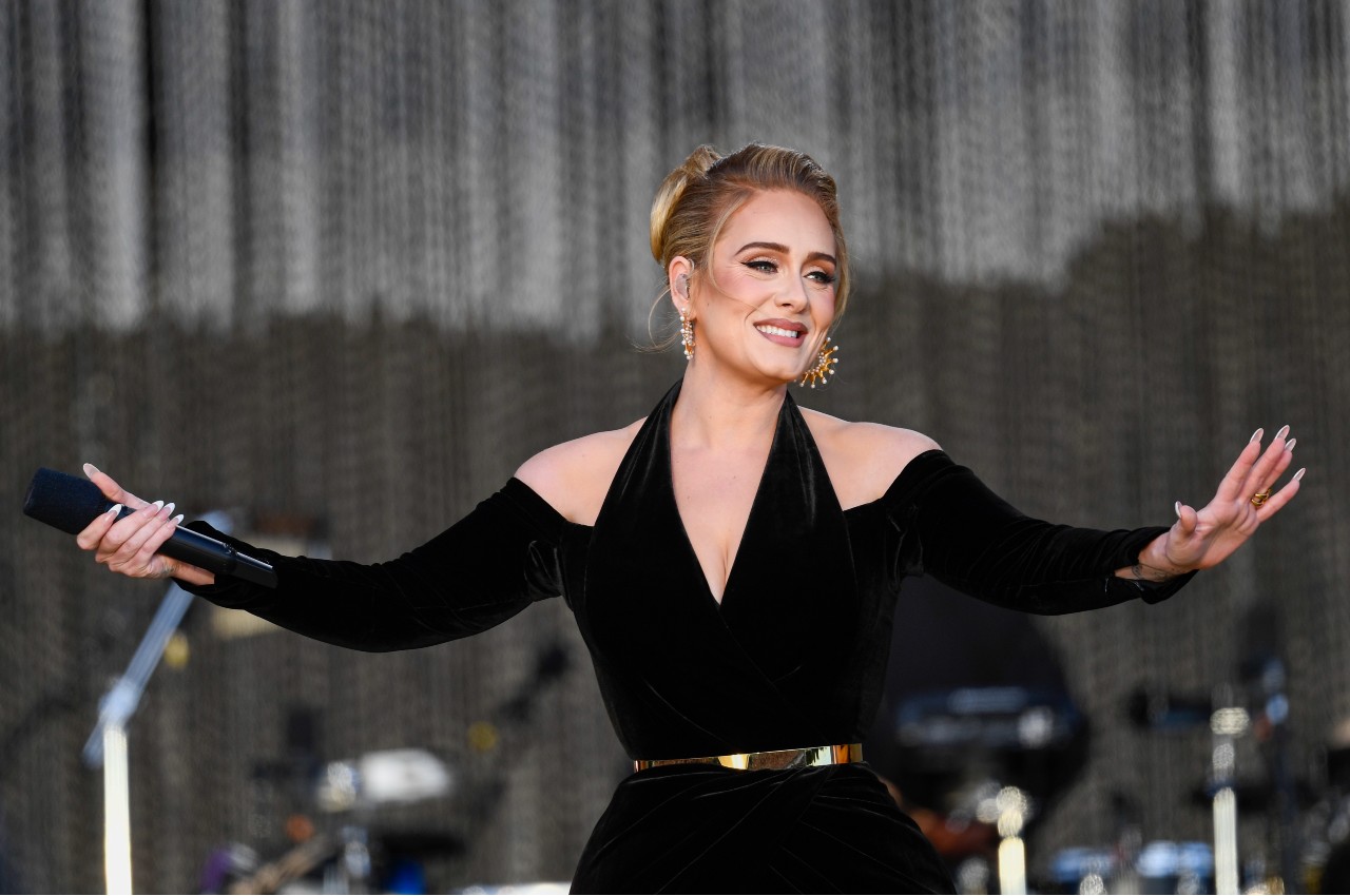 Adele holds a microphone during her concert.