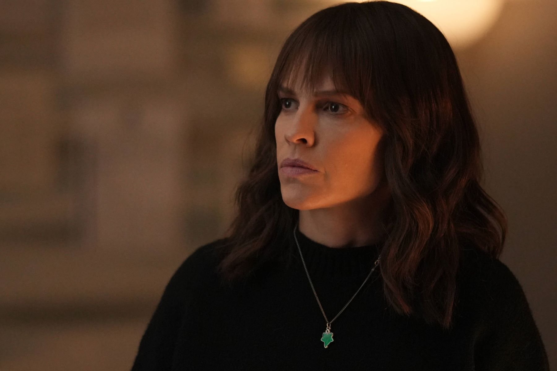 Hilary Swank, in character as Eileen Fitzgerald in 'Alaska Daily' Episode 7 on ABC, wears a black sweater and silver necklace with a green charm.
