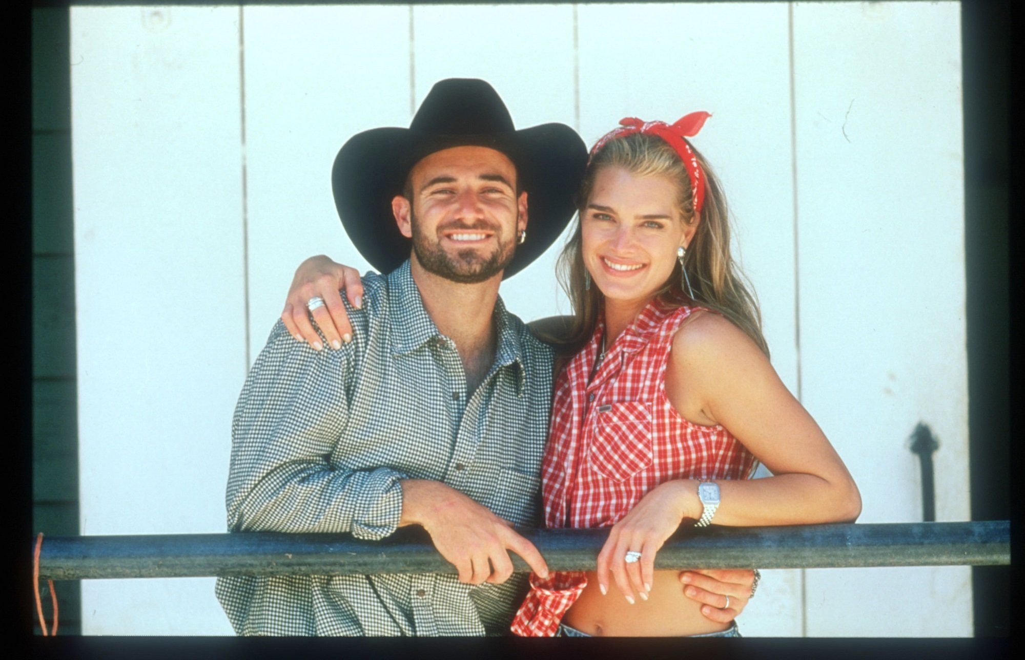 Andre Agassi in a black cowboy hat smiles with Brooke Shields in a red-checkered shirt