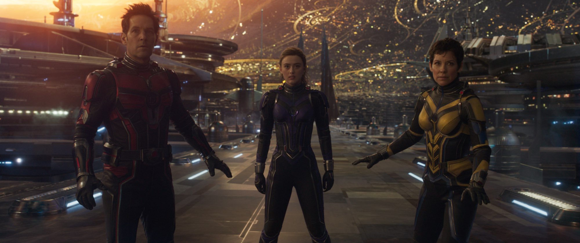 'Ant-Man and the Wasp: Quantumania' Paul Rudd as Scott Lang, Kathryn Newton as Cassie Lang, and Evangeline Lilly as Hope Van Dyne standing on a bridge wearing superhero suits