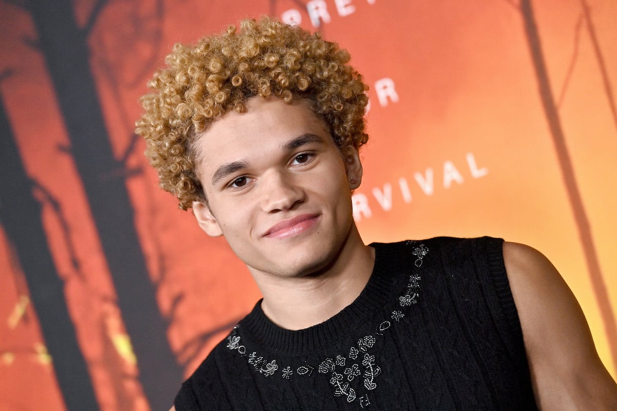 Armani Jackson poses for photos in front of an orange backdrop with the "Wolf Pack" logo.