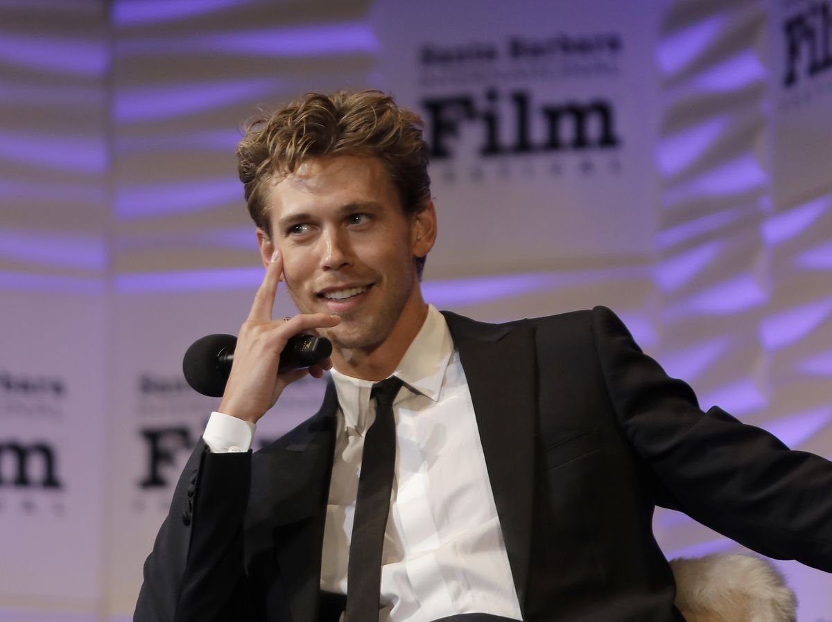 Austin Butler holds a microphone onstage at an awards ceremony.