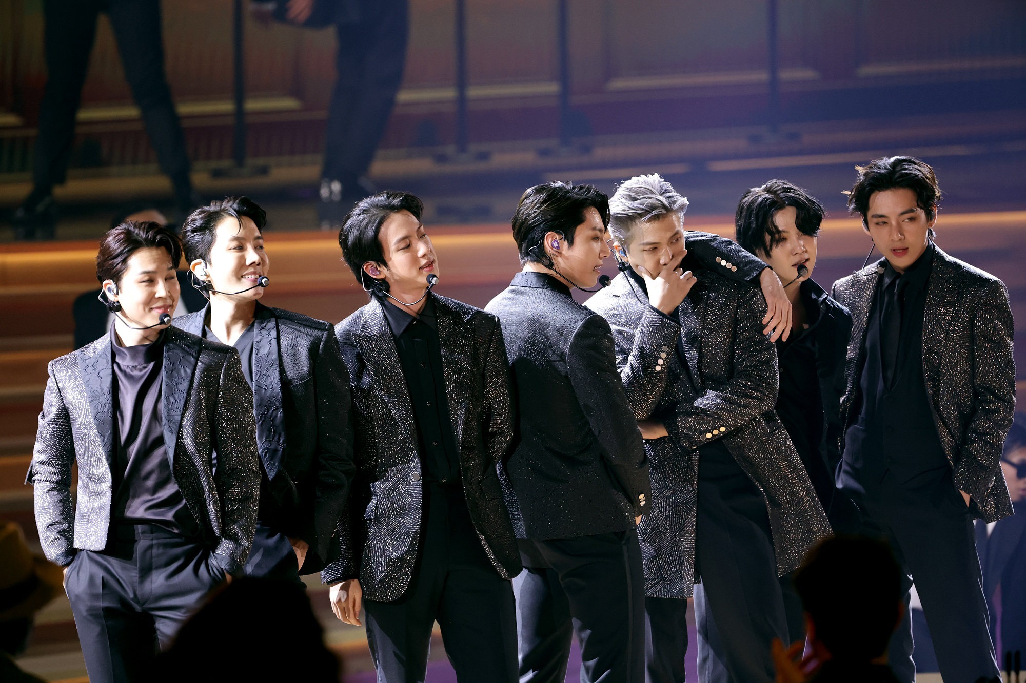 Jimin, J-Hope, Jin, Jungkook, RM, Suga, and V of BTS stand onstage at the 2022 Grammy Awards