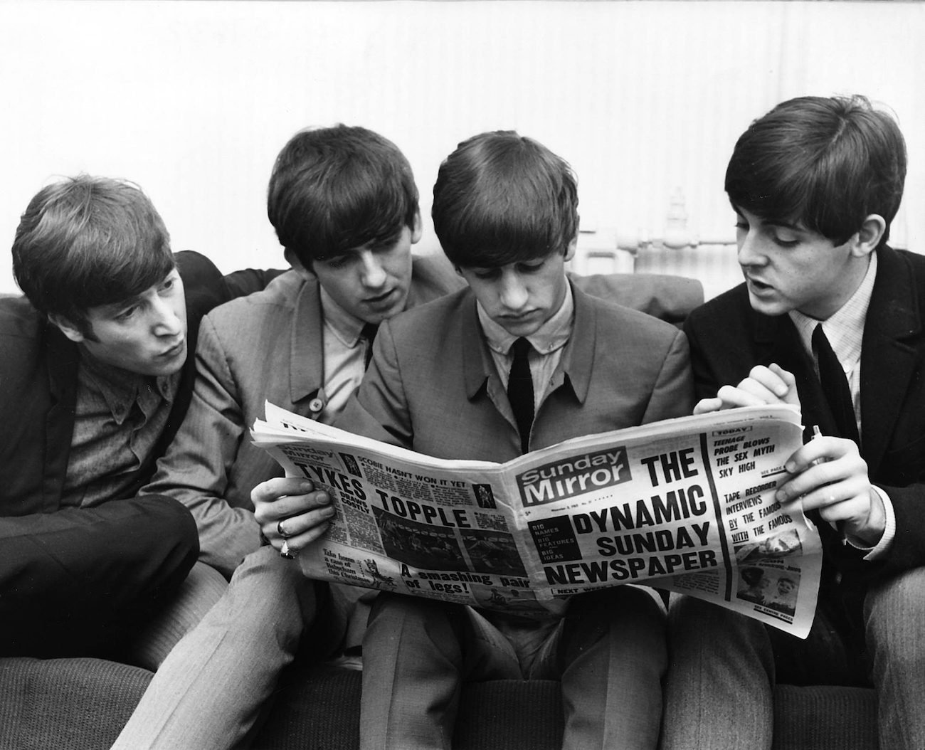 The Beatles reading the newspaper in suits in 1963.