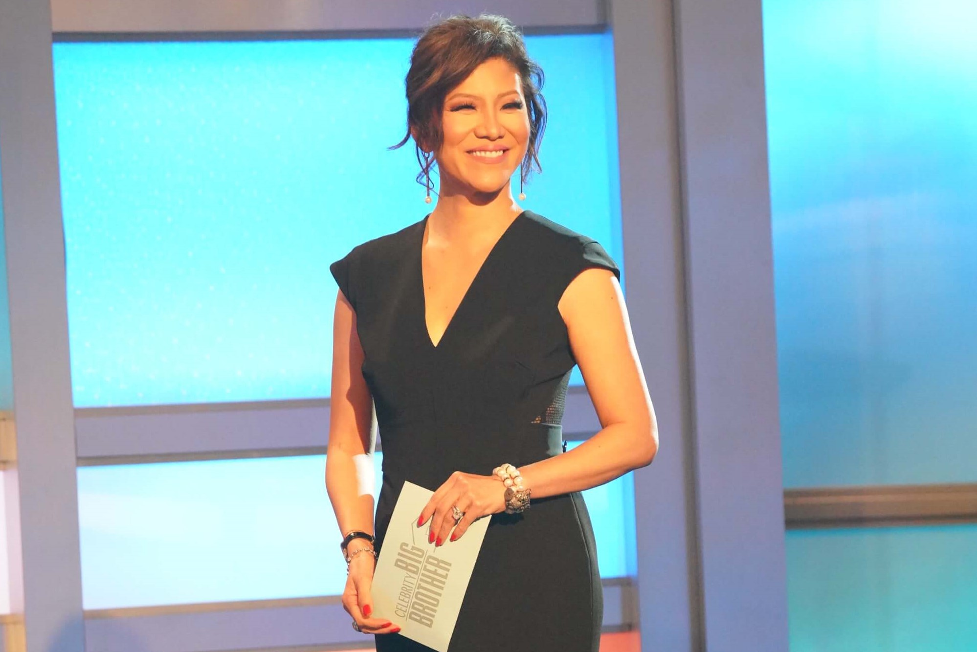 Julie Chen Moonves, the host of every season of 'Big Brother' on CBS, appears onstage in a black dress holding an envelope that says 'Big Brother' on it.
