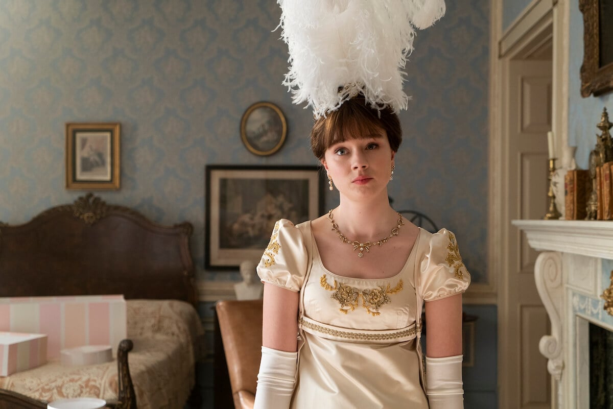 Claudia Jessie as Eloise Bridgerton wearing a large feather headpiece in 'Bridgerton'