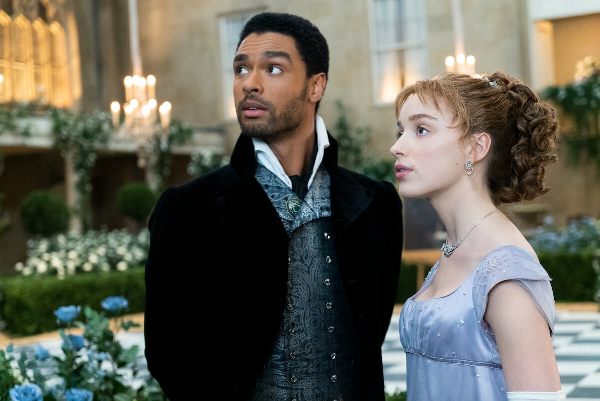 REGÉ-JEAN PAGE as SIMON BASSET and PHOEBE DYNEVOR as DAPHNE BRIDGERTON looking off to the side in 'BRIDGERTON' |