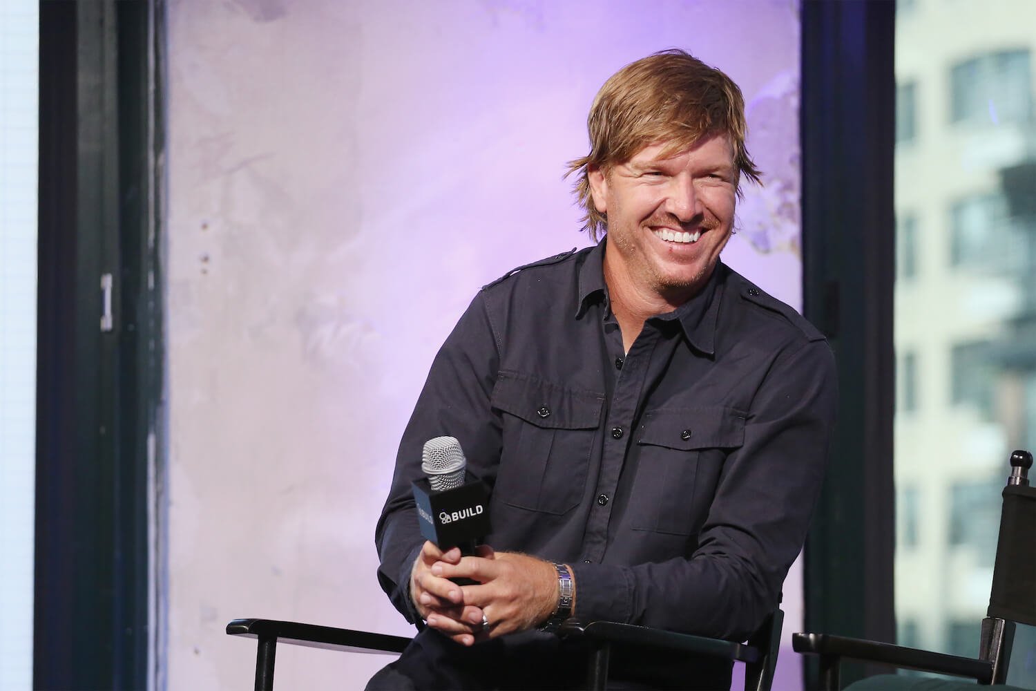 Chip Gaines, husband of Joanna Gaines, laughing with a microphone in his hand